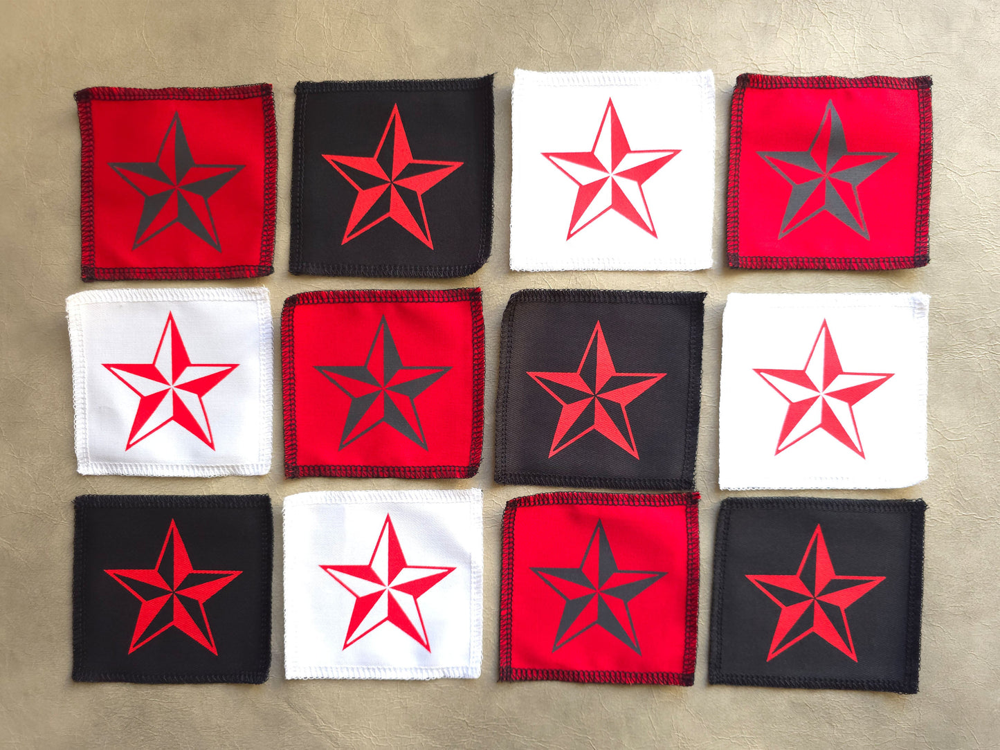 handmade screen printed Collection of red, black, and white fabric patches with star designs arranged in a grid on a beige surface.