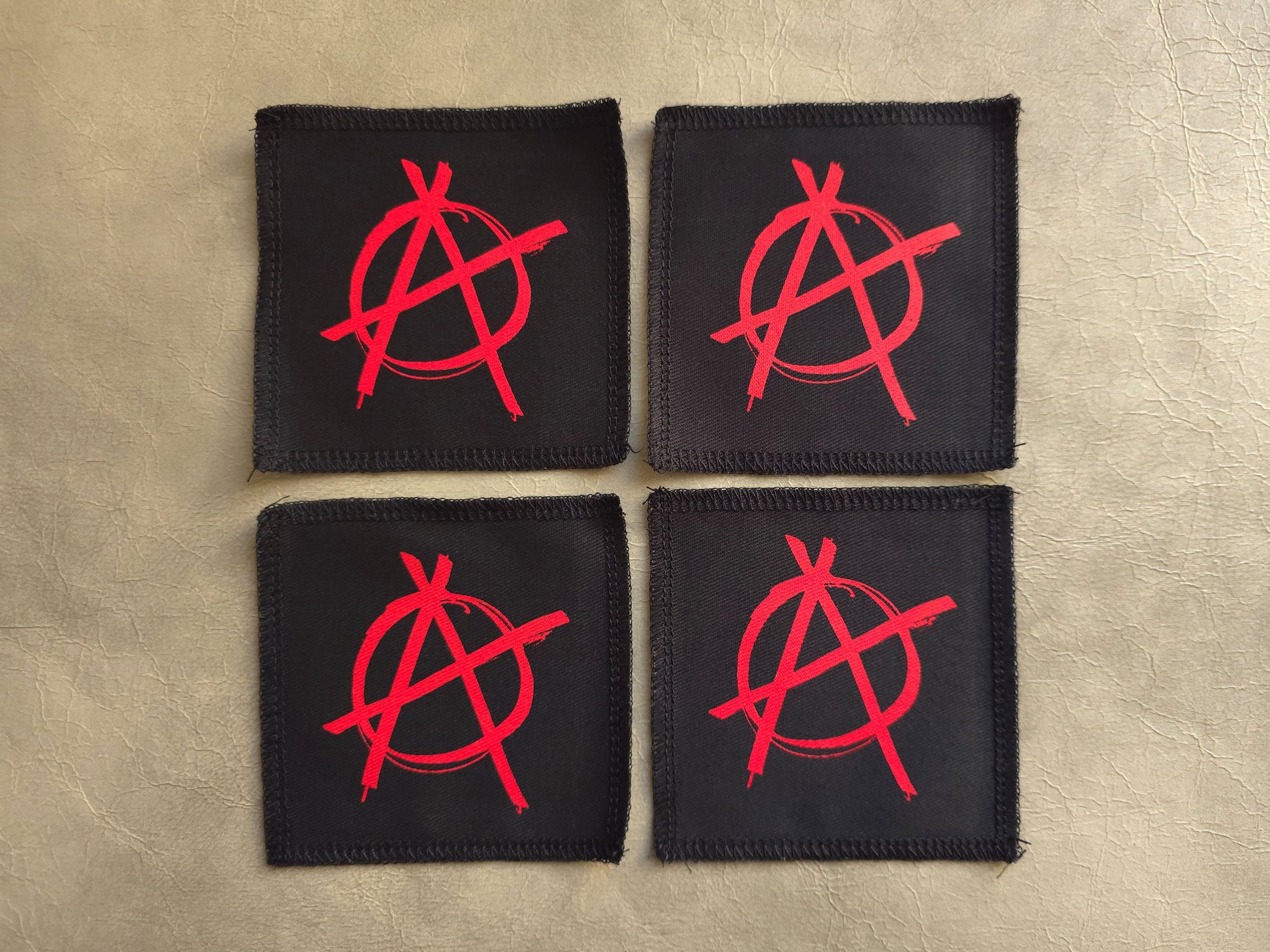 Black handmade screen printed anarchy symbol patches displayed together