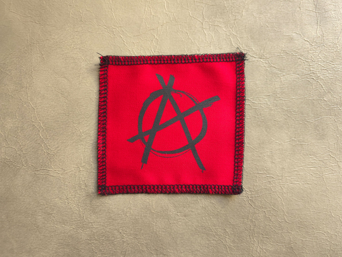 Red handmade screen printed anarchy symbol patch featuring bold printed symbol