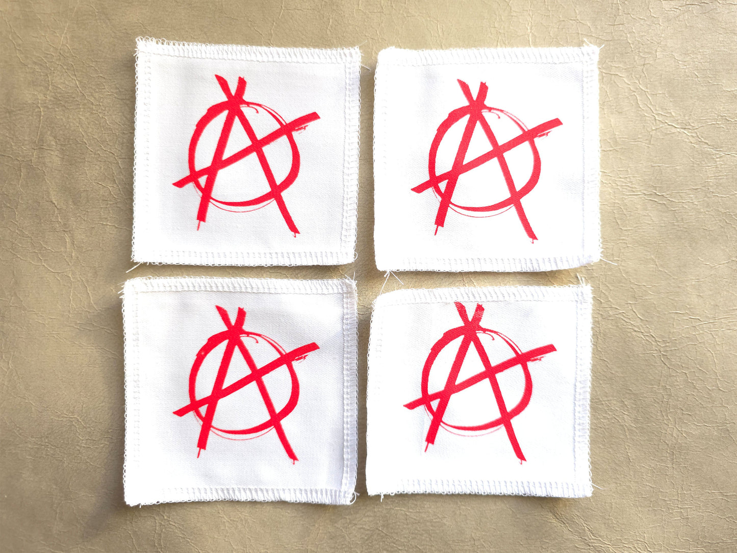 White handmade screen printed anarchy symbol patches displayed as a set