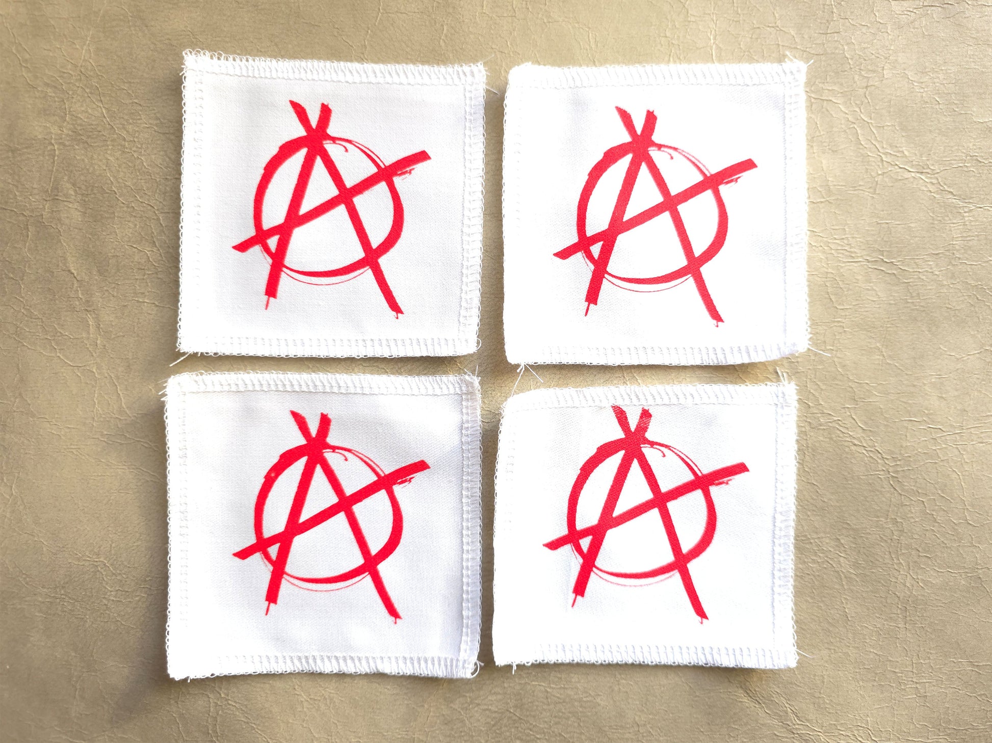 White handmade screen printed anarchy symbol patches displayed as a set