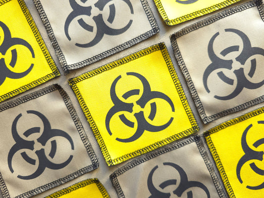Angled view of handmade screen printed biohazard symbol patch highlighting fabric texture and print detail