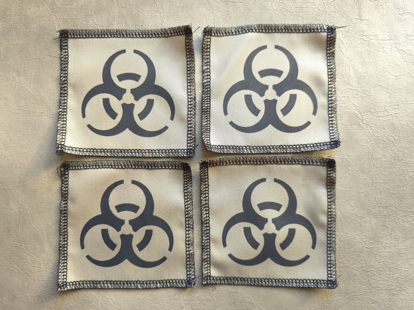 Beige handmade screen printed biohazard symbol patches arranged in a group display