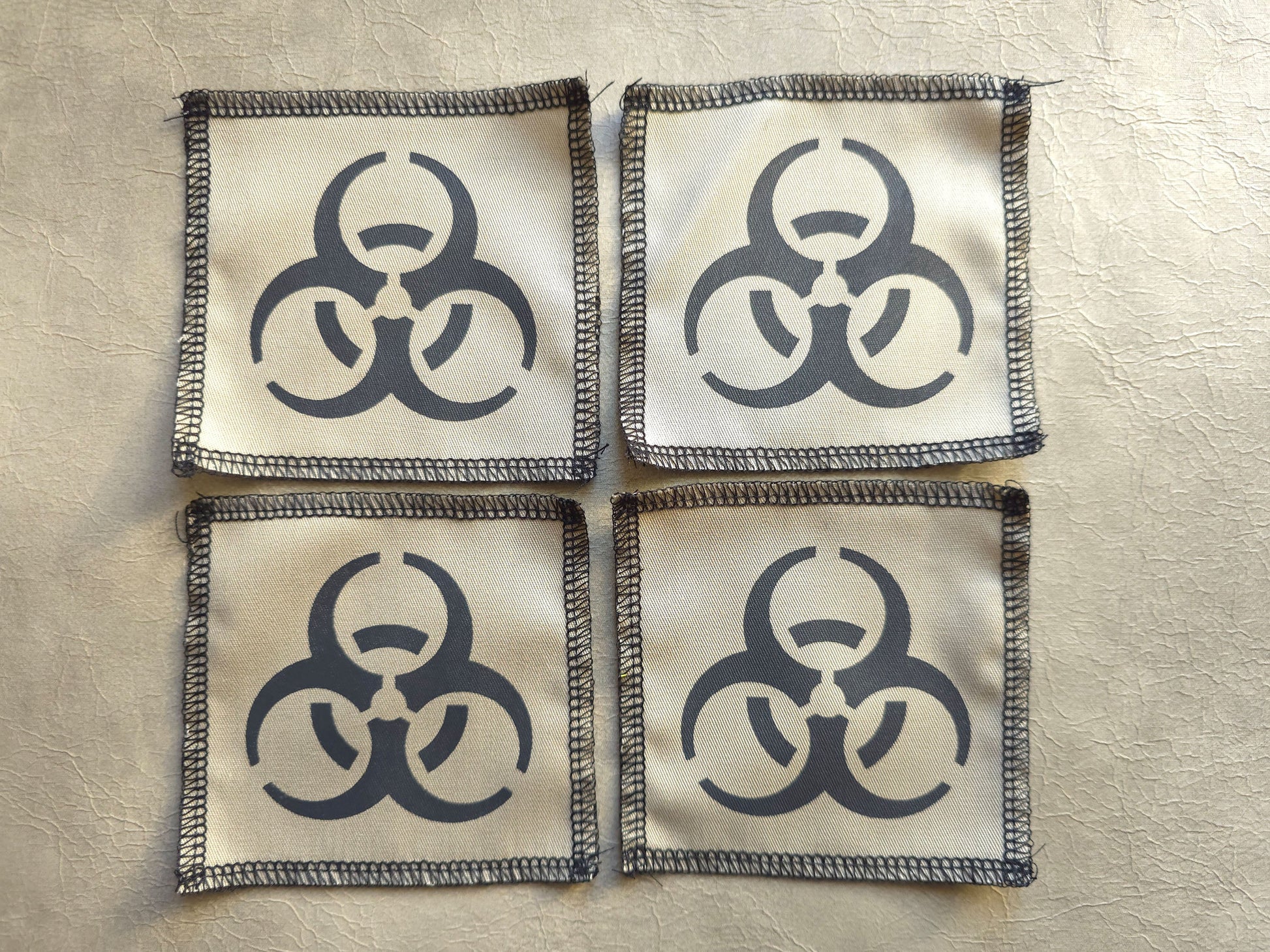 Beige handmade screen printed biohazard symbol patches arranged in a group display