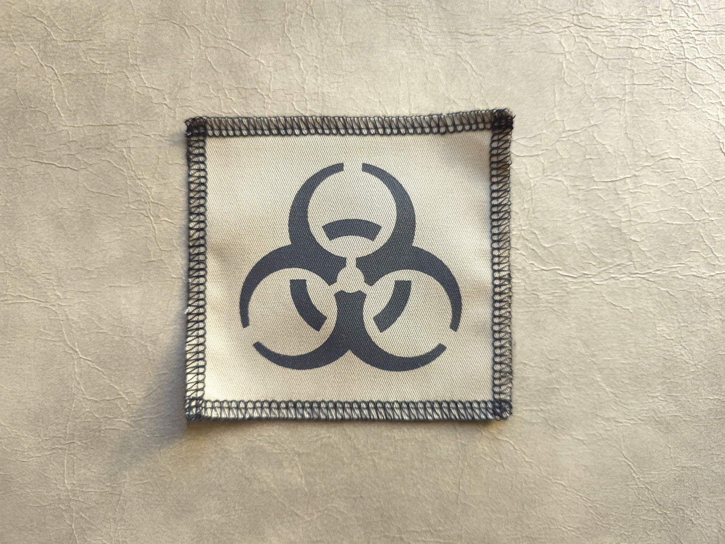 Beige handmade screen printed biohazard symbol patch with clean printed symbol design 
