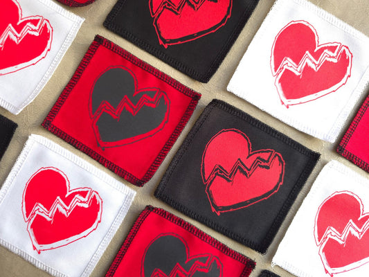 Angled view of handmade screen printed broken heart symbol patch highlighting fabric texture and print detail