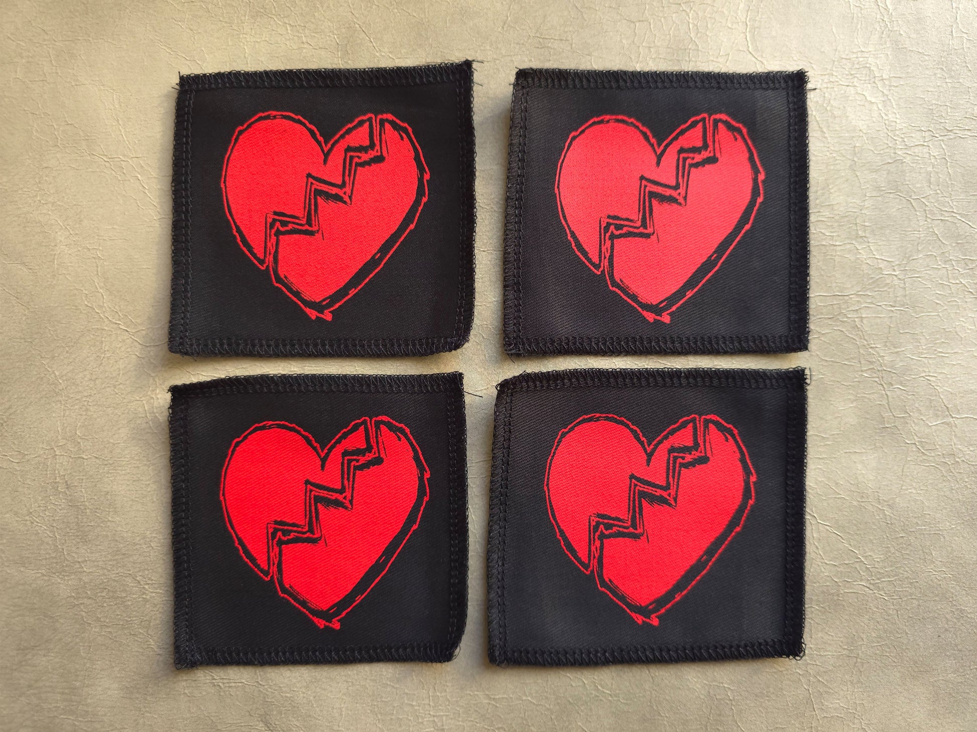 Black handmade screen printed broken heart symbol patches displayed together