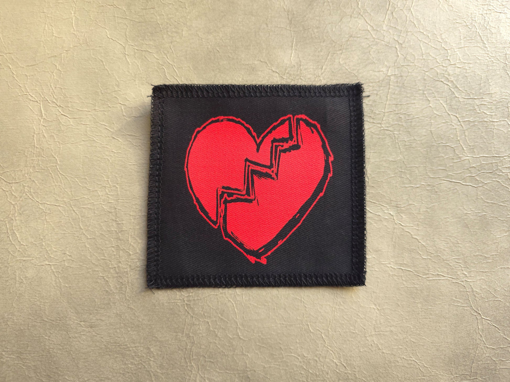 Black handmade screen printed broken heart symbol patch with high-contrast printed graphic