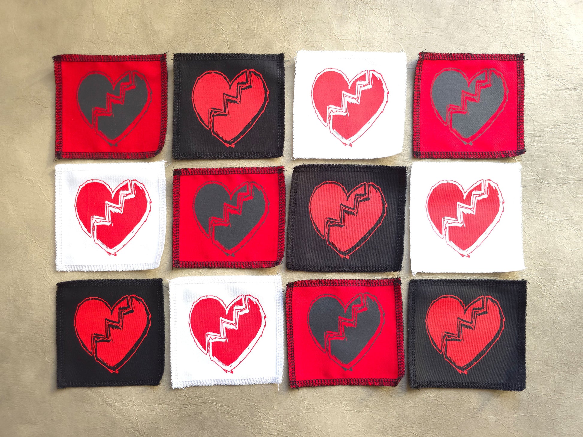 Assorted handmade screen printed broken heart symbol patches displayed together in different colors