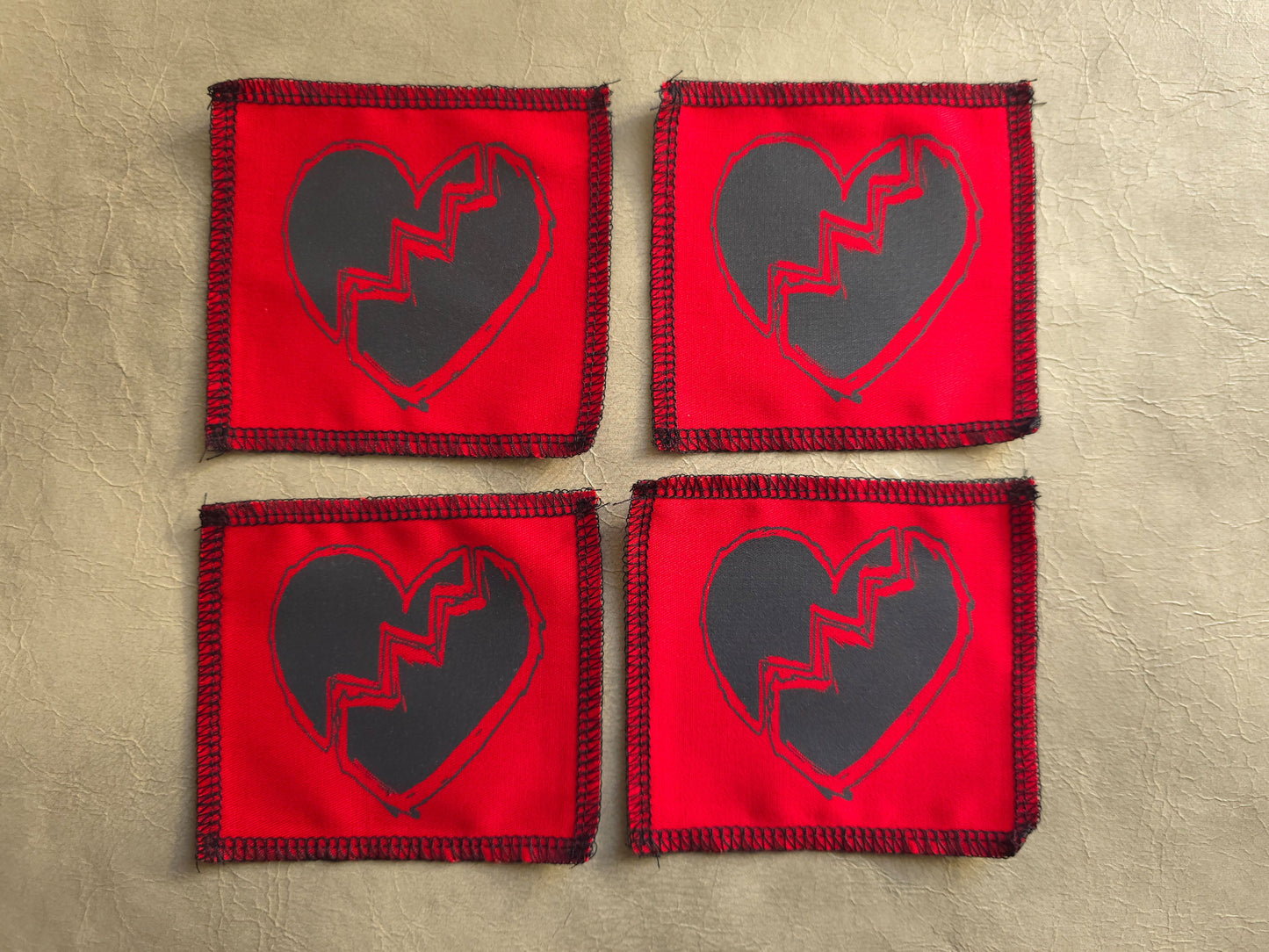Red handmade screen printed broken heart symbol patches arranged as a collection