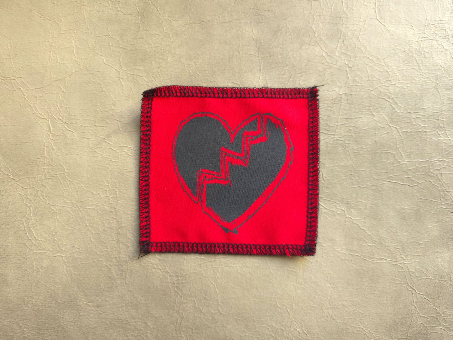 Red handmade screen printed broken heart symbol patch featuring bold printed symbol