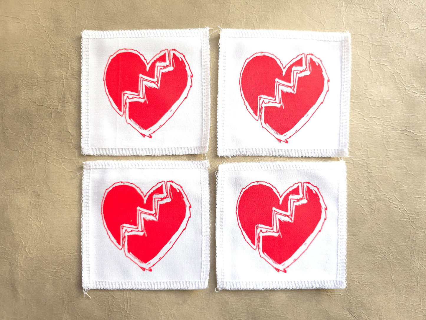 White handmade screen printed broken heart symbol patches displayed as a set