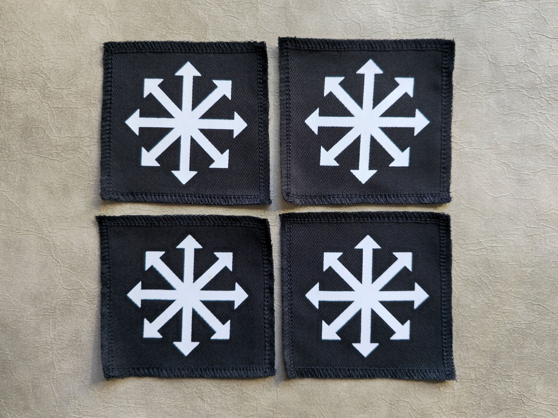 Black handmade screen printed chaos symbol patches displayed together