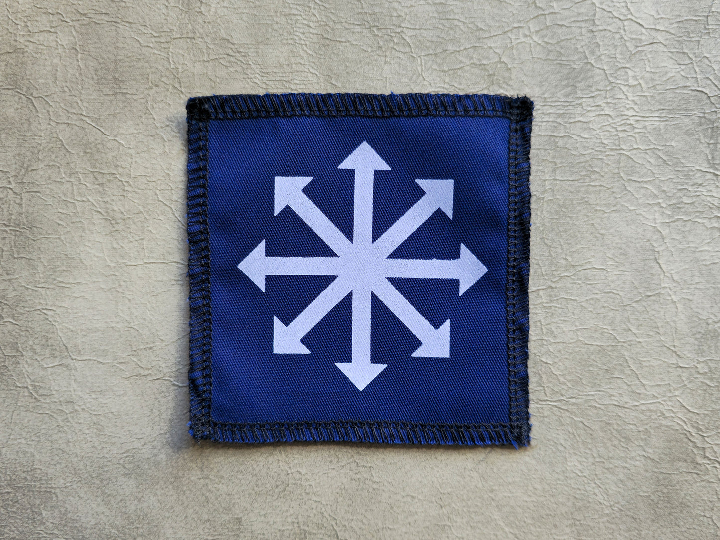 Blue handmade screen printed chaos symbol patch with contrasting ink detail