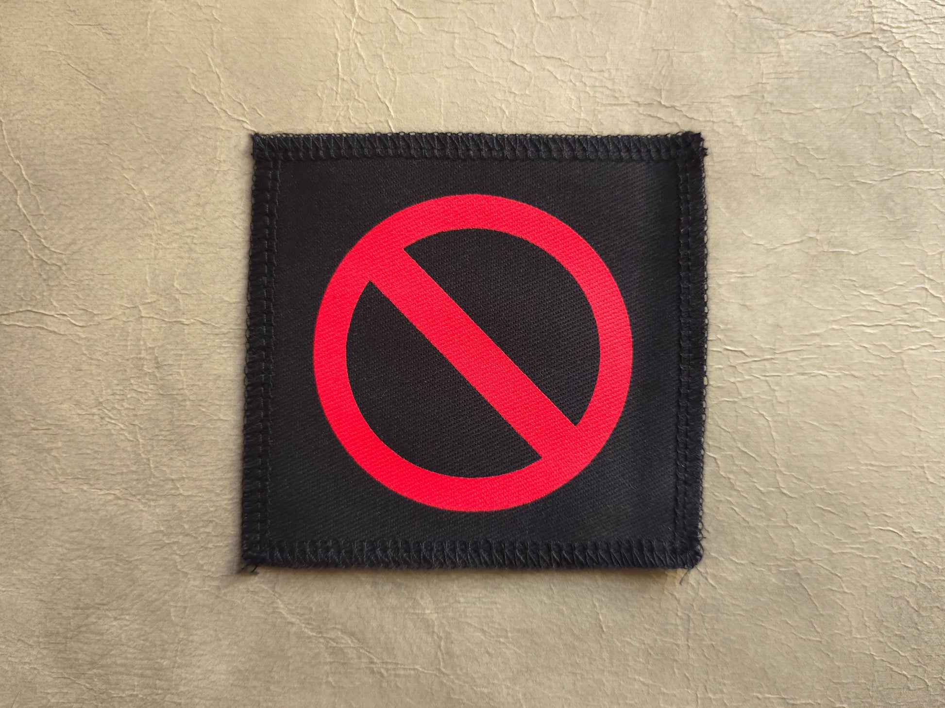 Black handmade screen printed crossed circle symbol patch with high-contrast printed graphic