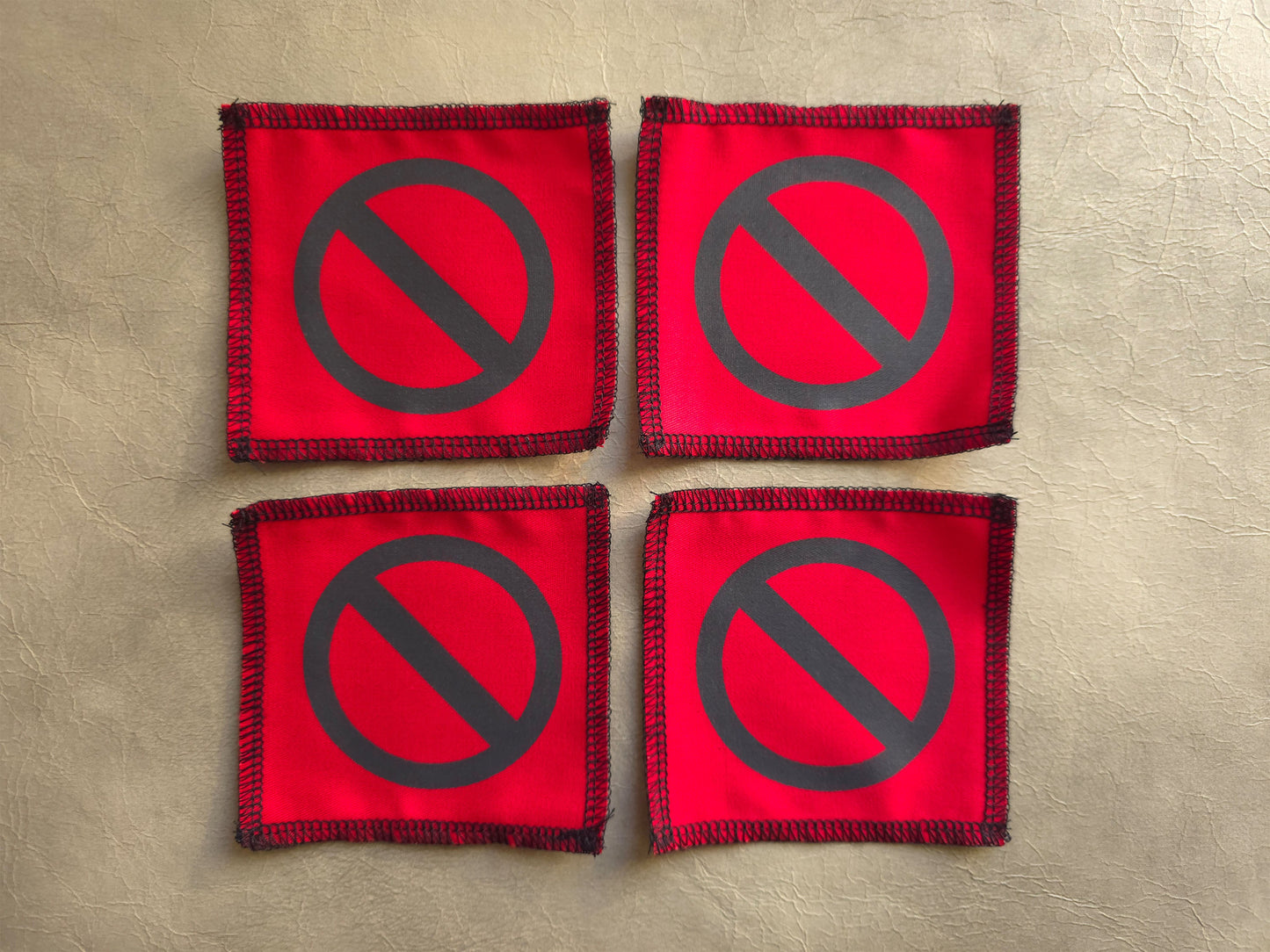 Red handmade screen printed crossed circle symbol patches arranged as a collection