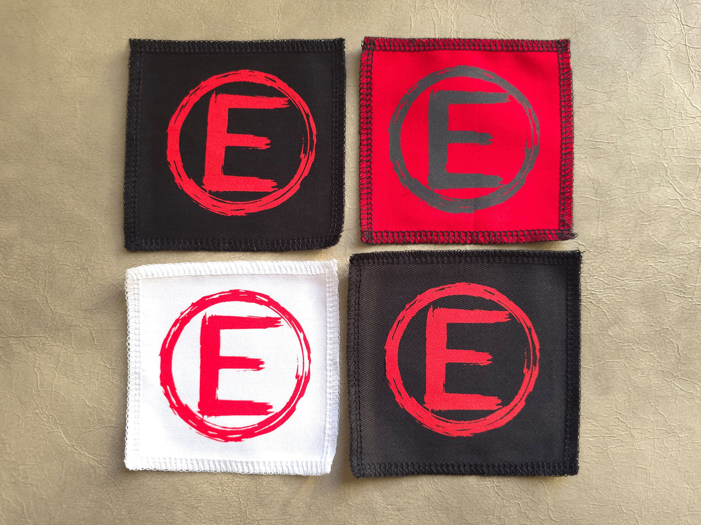  square patches with letter 'E' design on a beige background