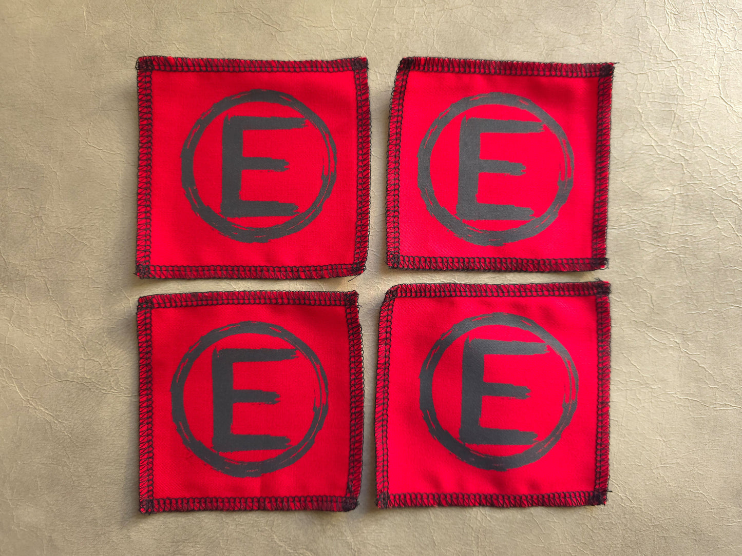 handmade screen printed red square patches with a central black letter 'E' - equality symbol