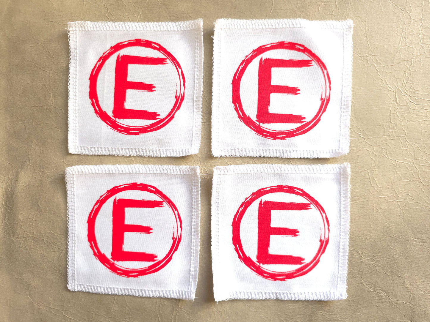handmade screen printed white square patches with red 'E' logo - equality symbol