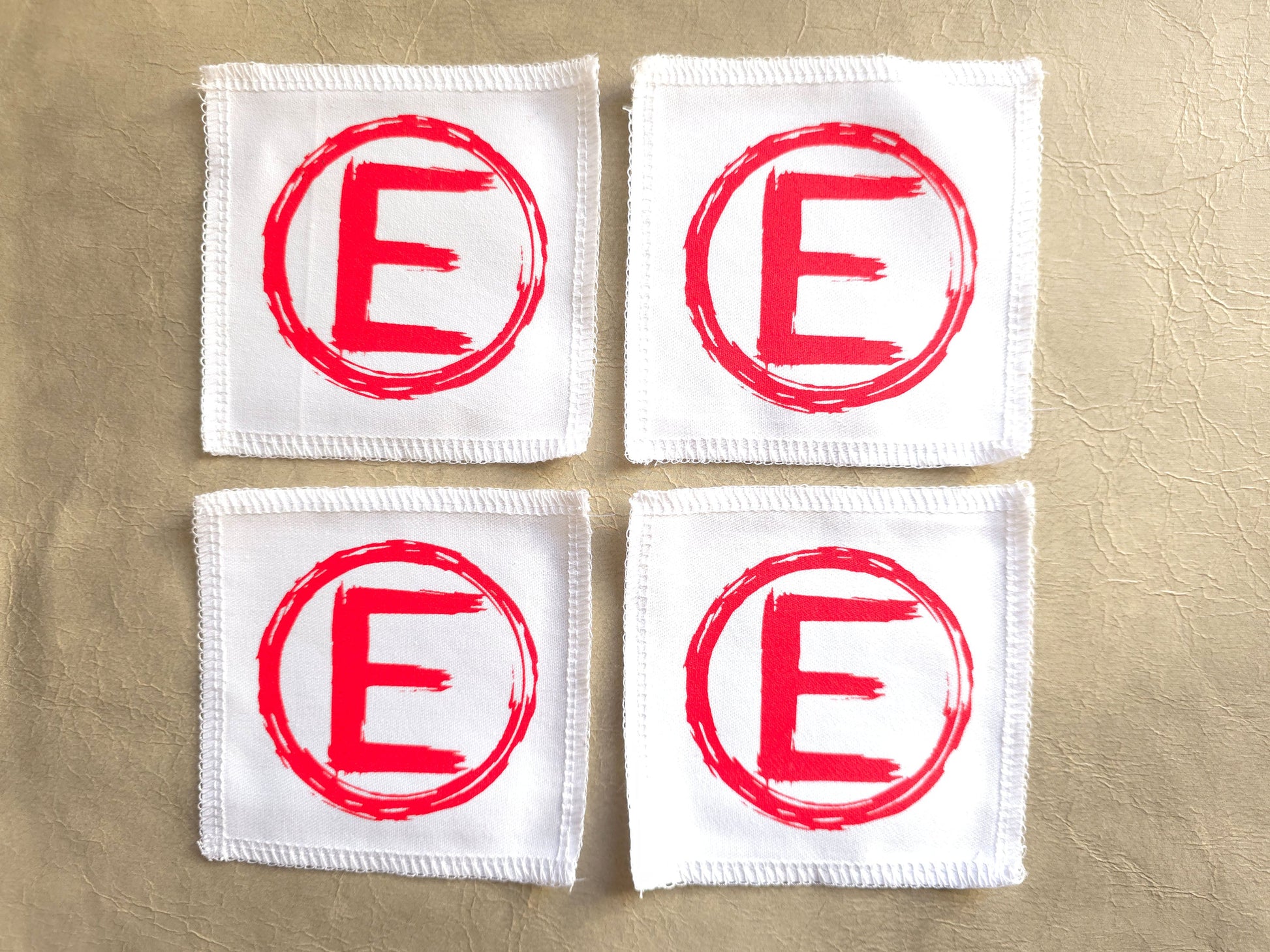 handmade screen printed white square patches with red 'E' logo - equality symbol