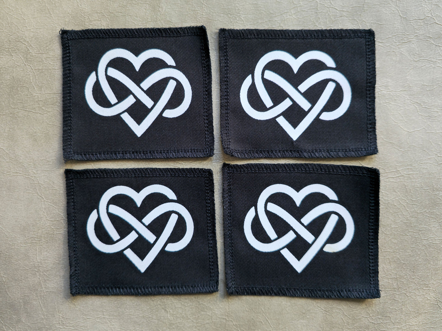 Black handmade screen printed forever love symbol patches displayed together