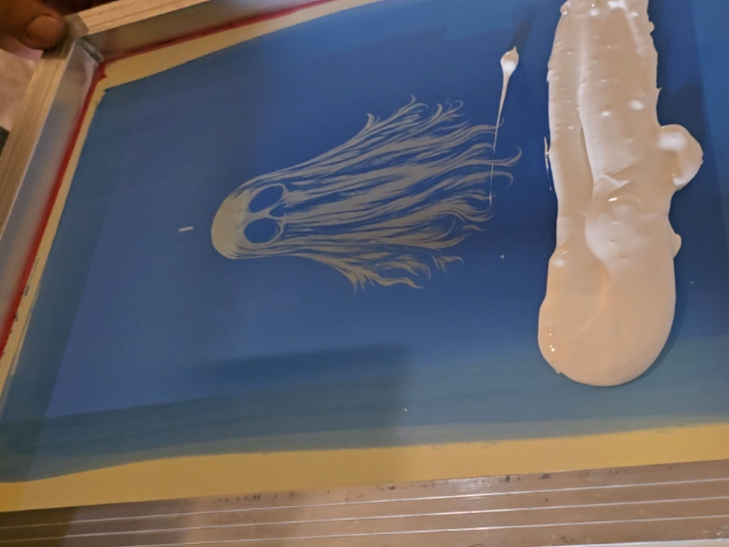 Artisan screen printing a handmade ghost patch with ink and mesh screen in studio workspace