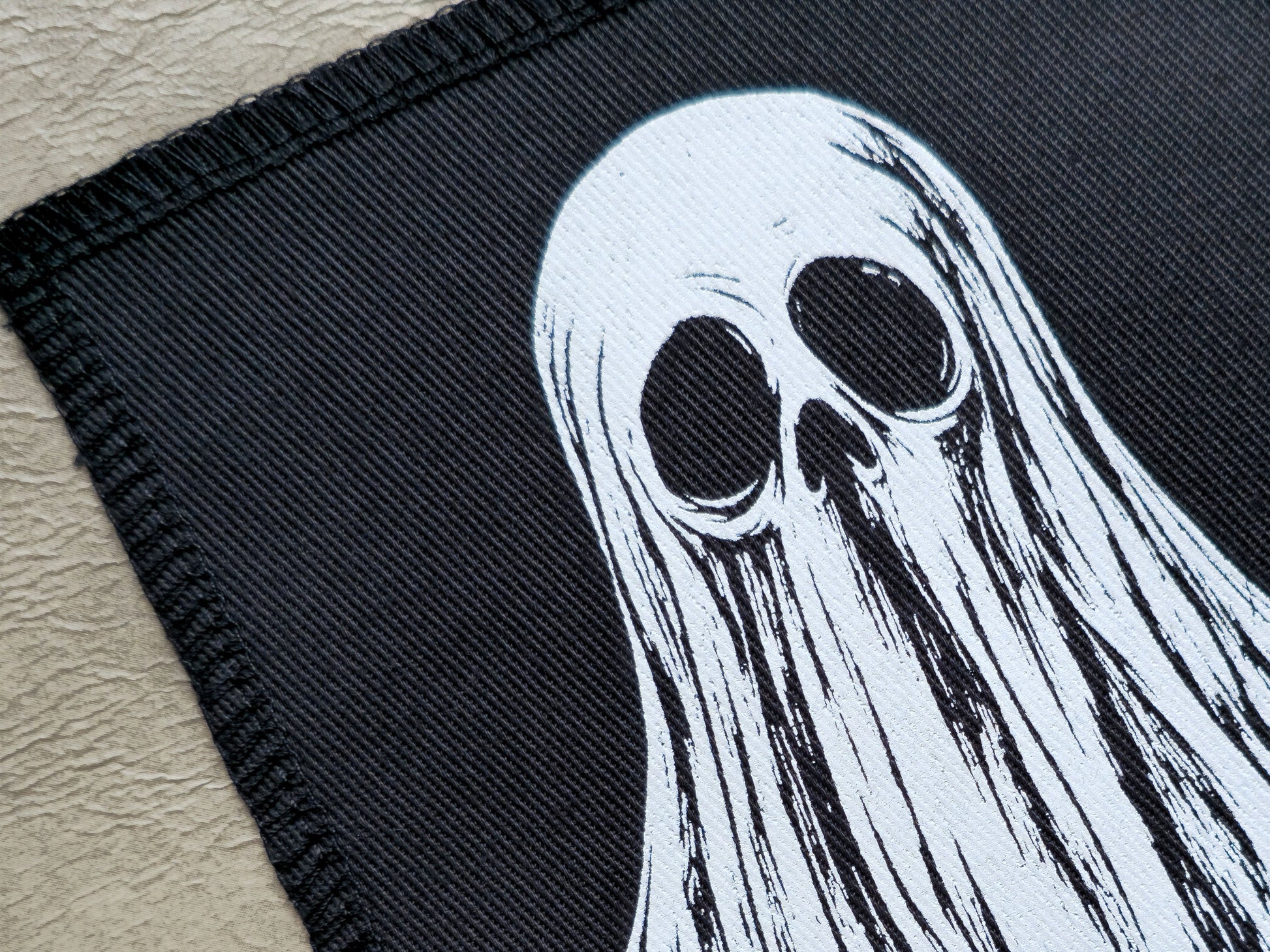 Close-up detail of handmade screen printed ghost patch showing ink texture and fine print lines
