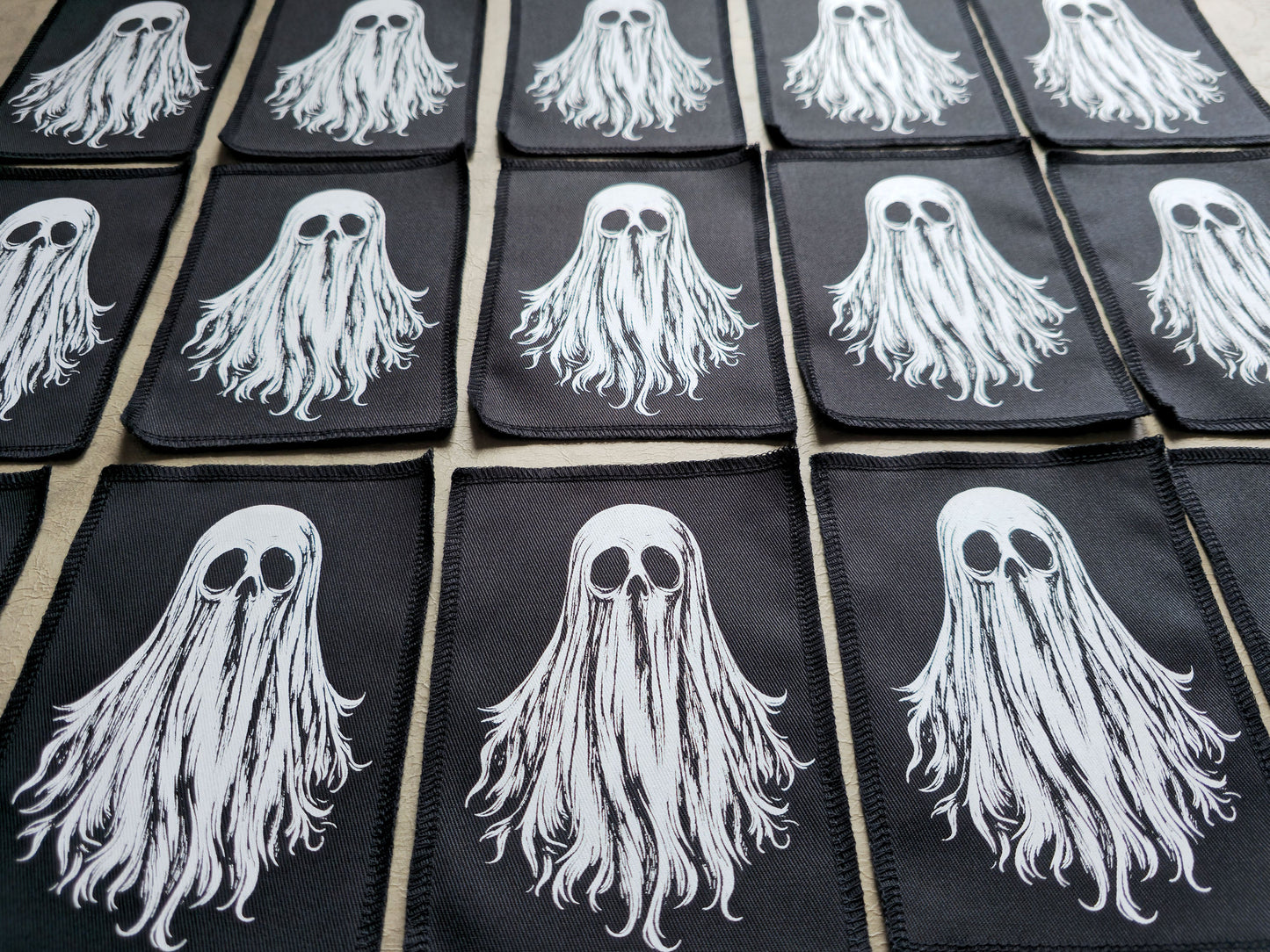 Detailed view of multiple handmade ghost patches highlighting stitching, fabric texture, and print quality