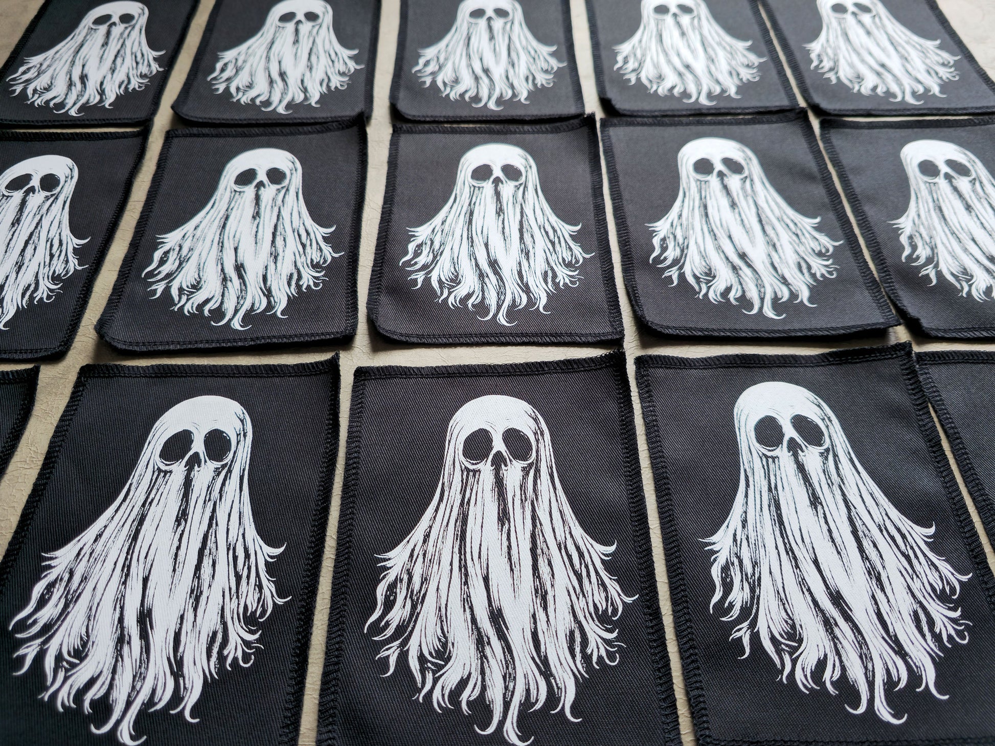Detailed view of multiple handmade ghost patches highlighting stitching, fabric texture, and print quality