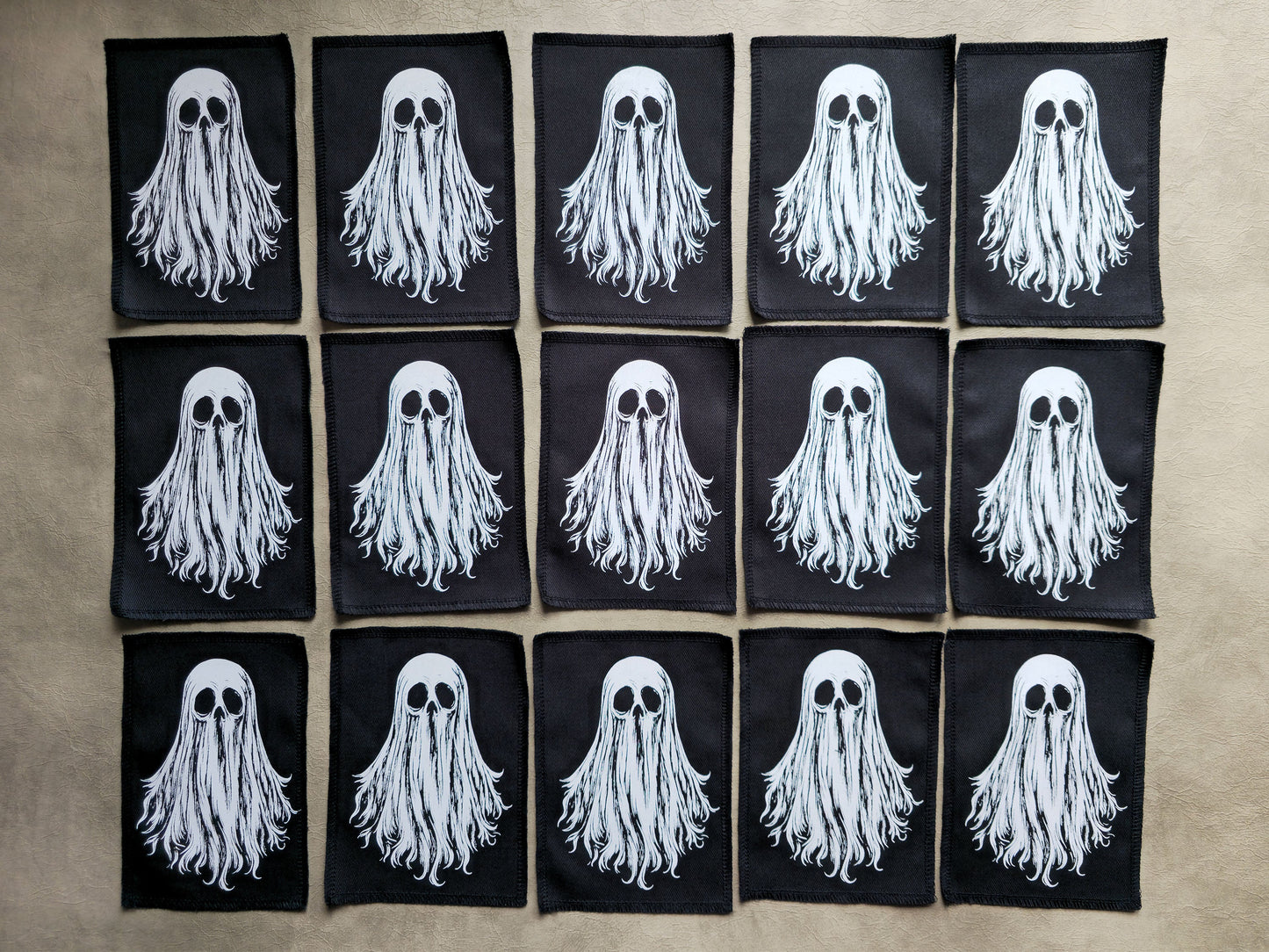 Group display of handmade screen printed ghost patches arranged together showcasing multiple ghosts