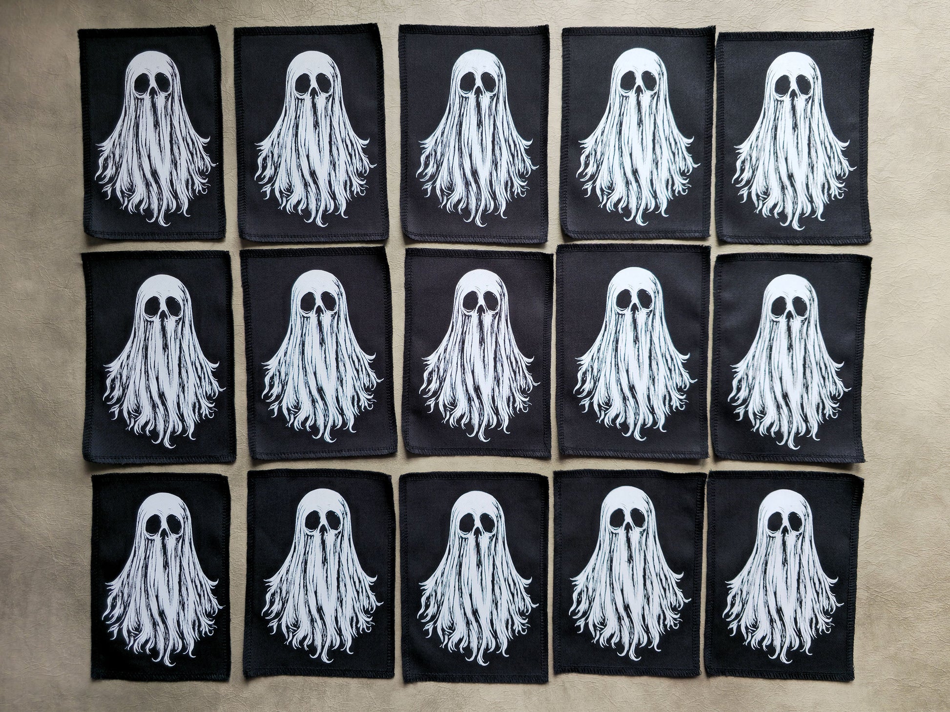 Group display of handmade screen printed ghost patches arranged together showcasing multiple ghosts