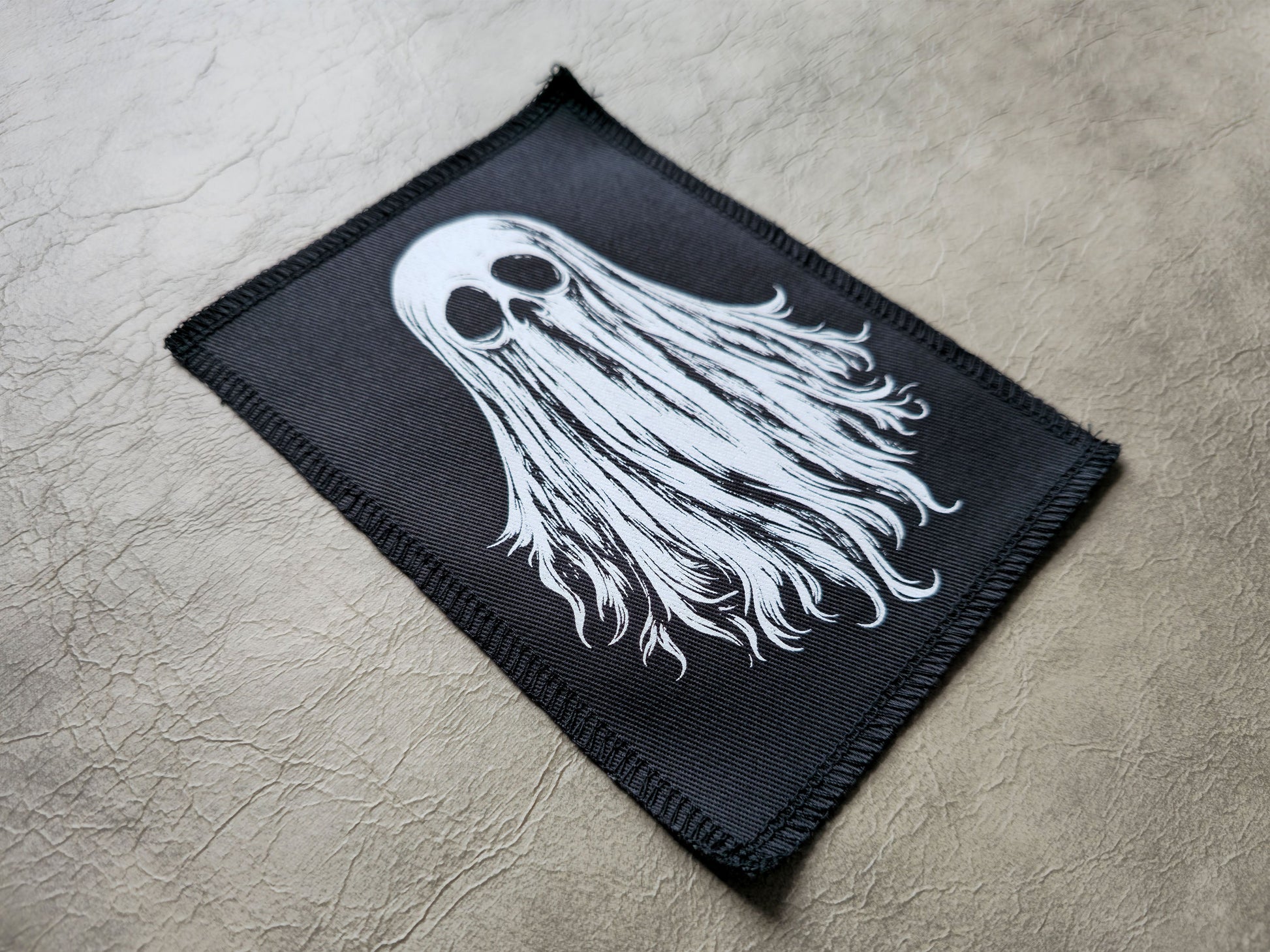 Side angle of handmade ghost patch highlighting fabric thickness, stitched edges, and screen printed surface