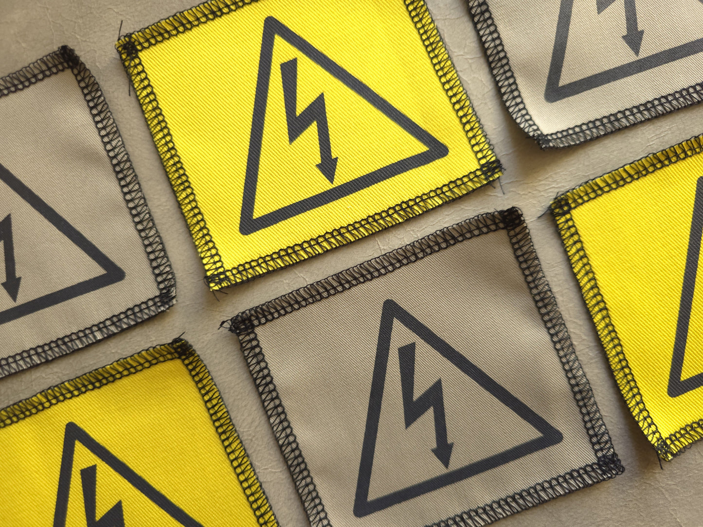 Angled view of handmade screen printed high voltage symbol patch highlighting fabric texture and print detail