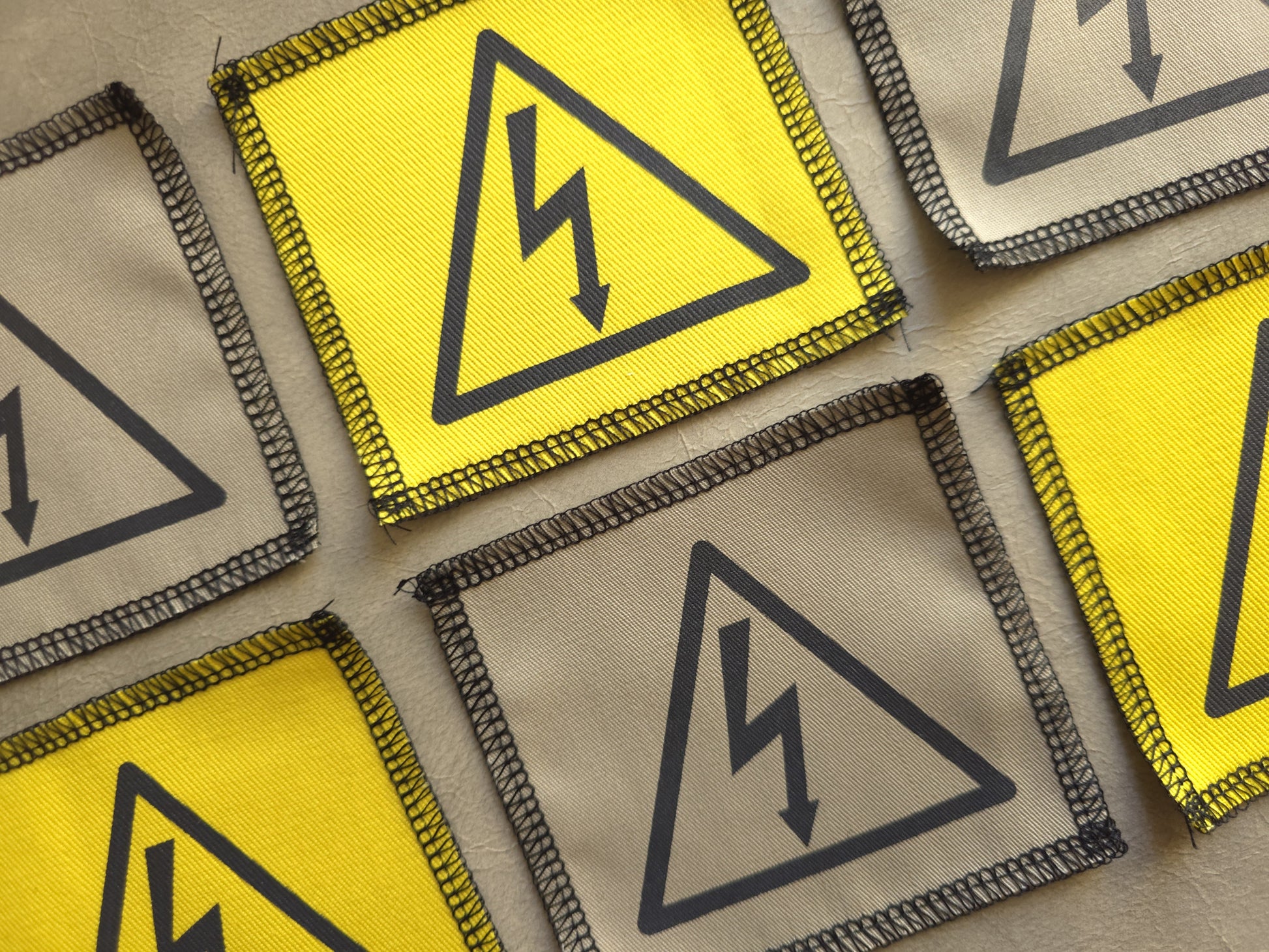 Angled view of handmade screen printed high voltage symbol patch highlighting fabric texture and print detail