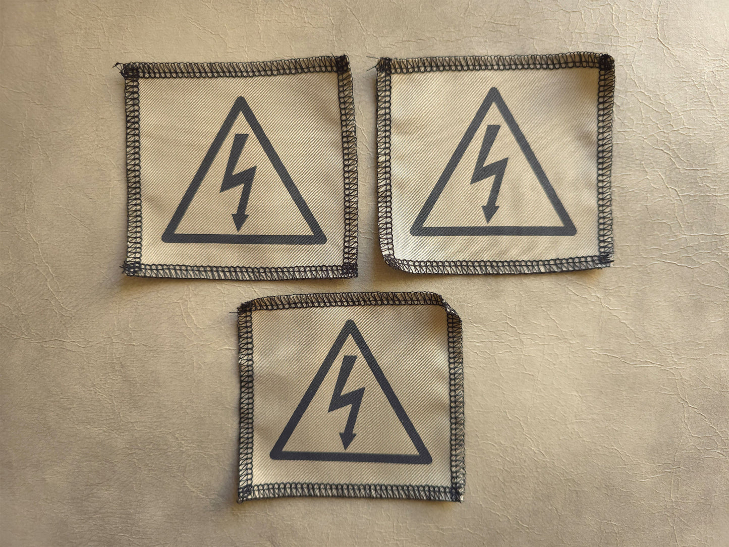 Beige handmade screen printed high voltage symbol patches arranged in a group display