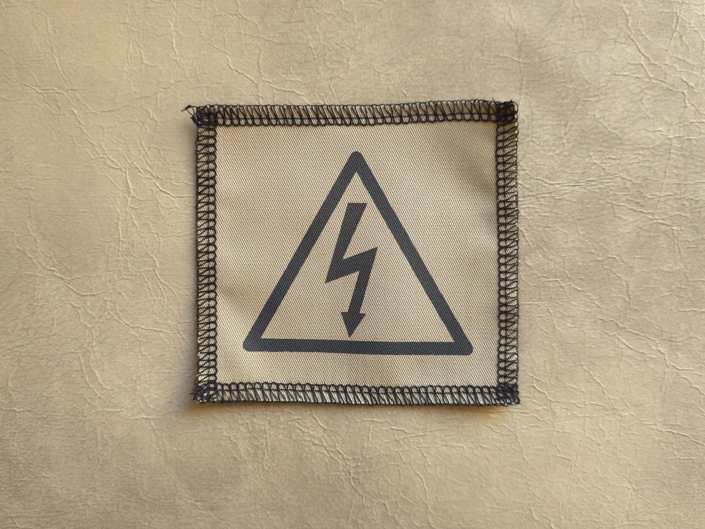 Fabric patch with a lightning bolt symbol on a beige background