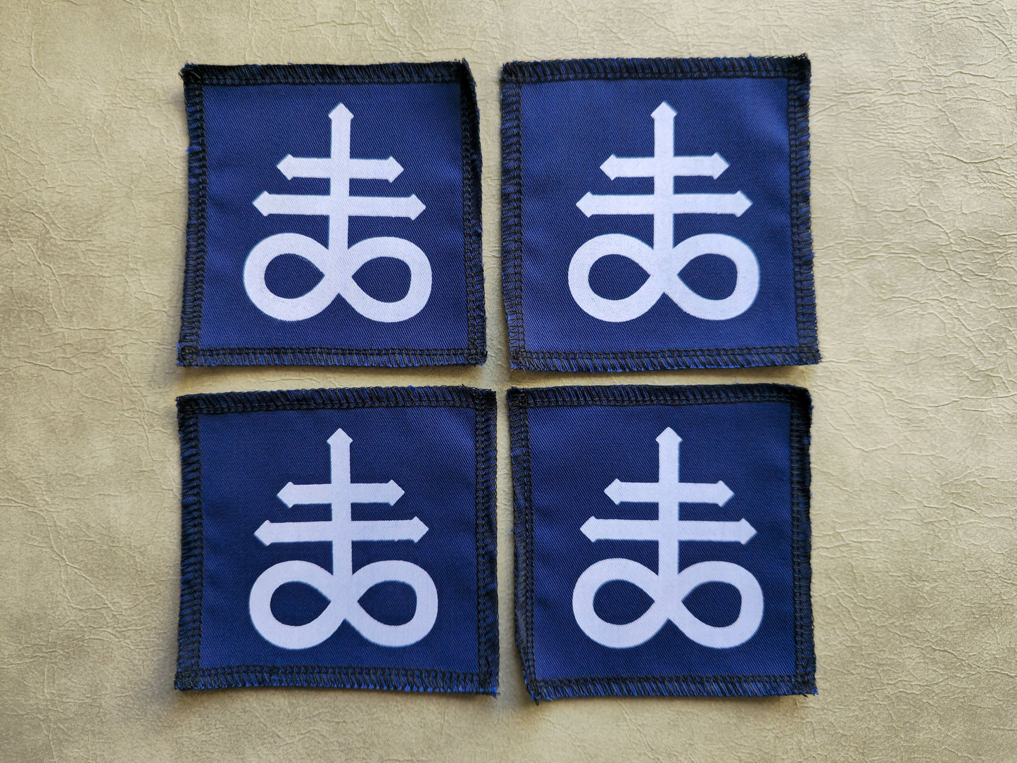 Blue handmade screen printed leviathan symbol patches shown as a coordinated set