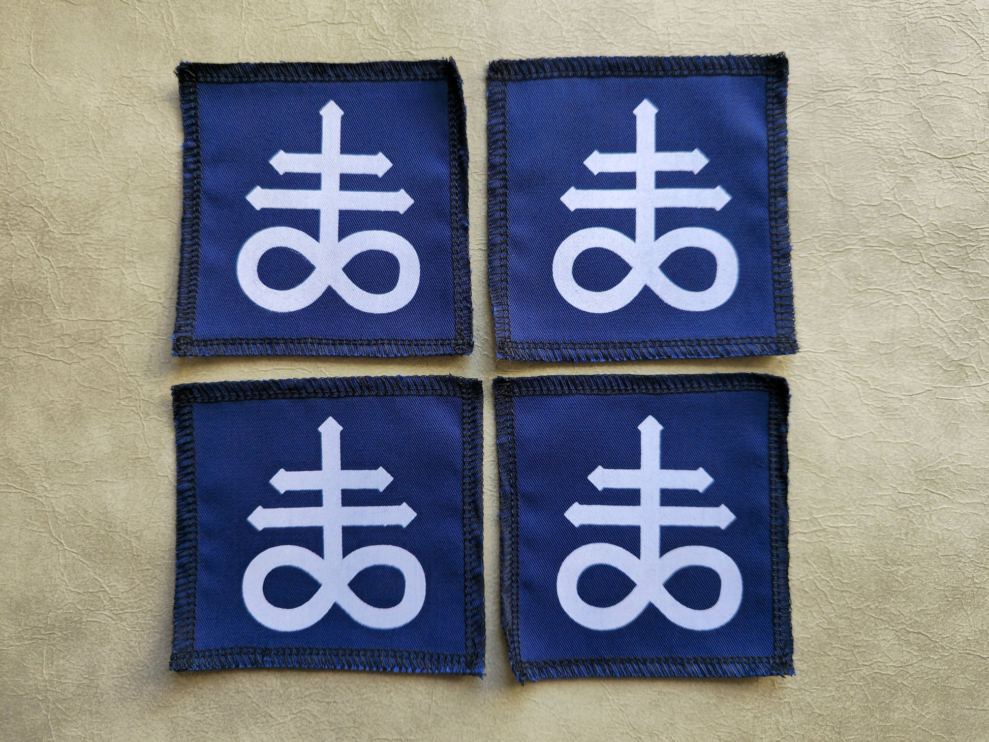 Blue handmade screen printed leviathan symbol patches shown as a coordinated set