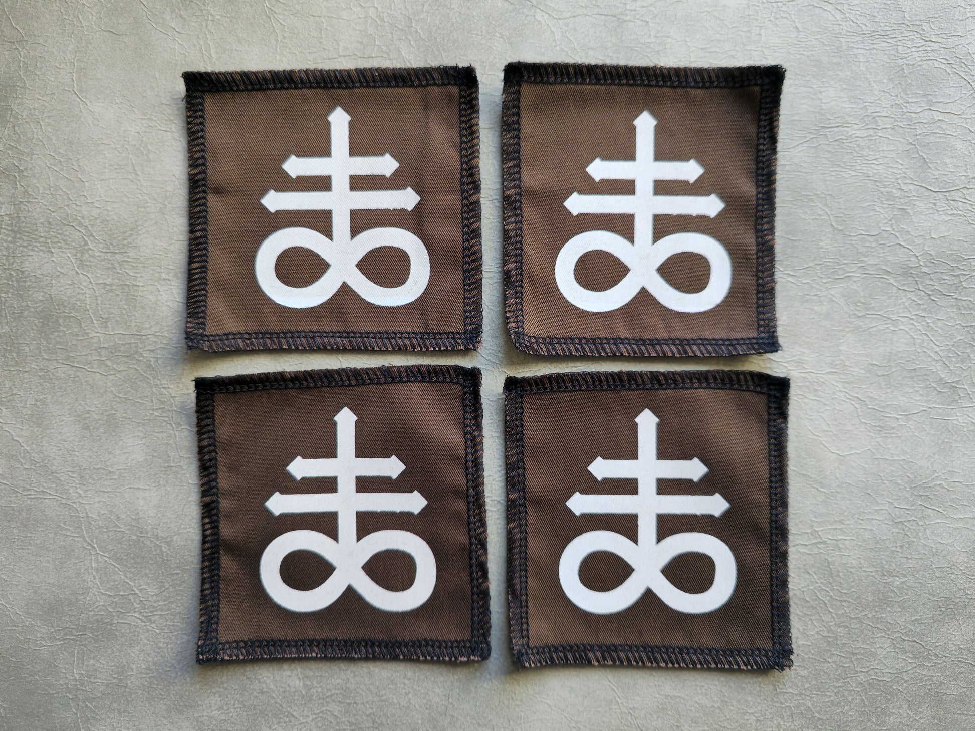 Brown handmade screen printed leviathan symbol patches displayed in a group layout