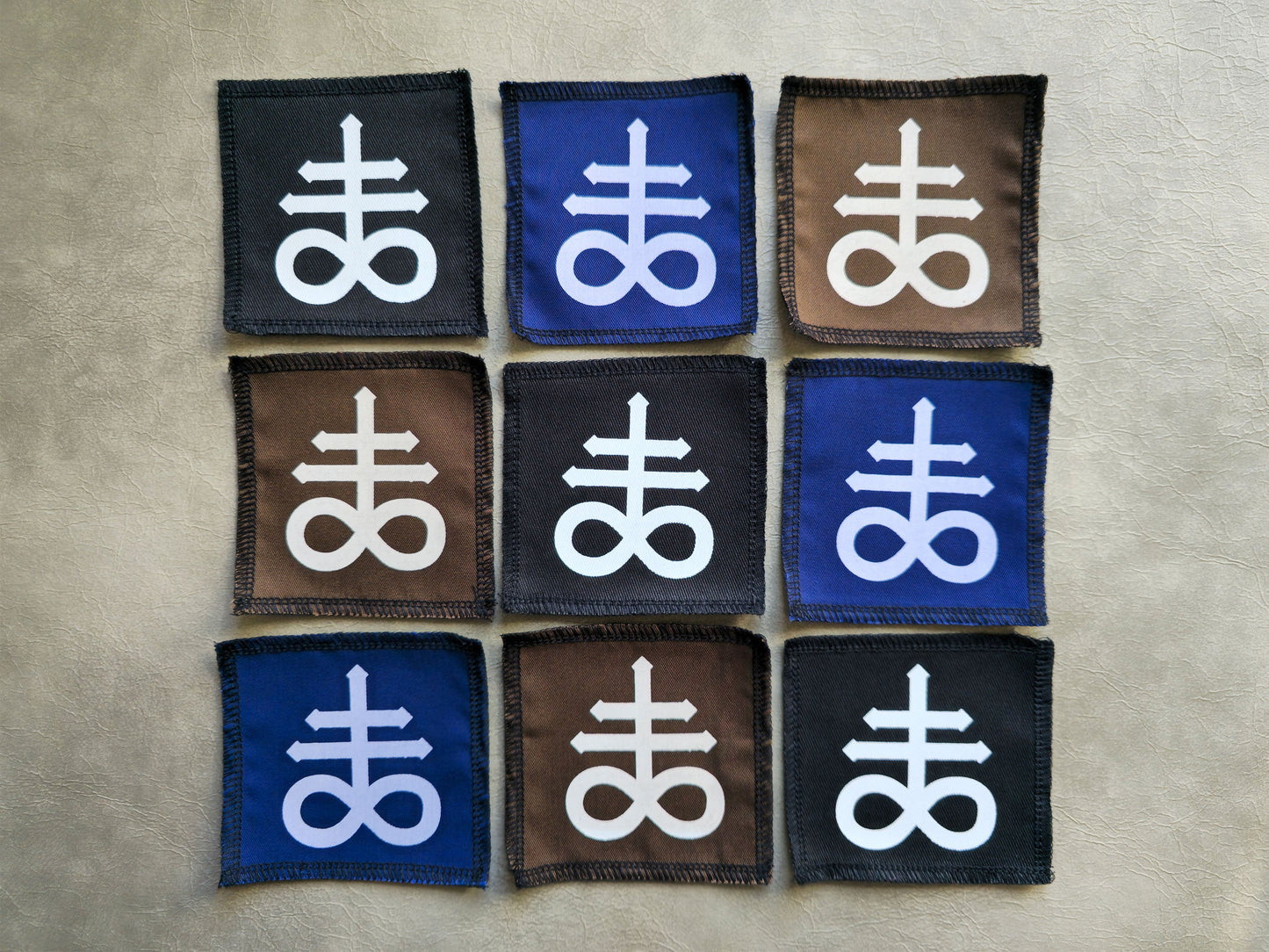 Assorted handmade screen printed leviathan symbol patches displayed together in different colors