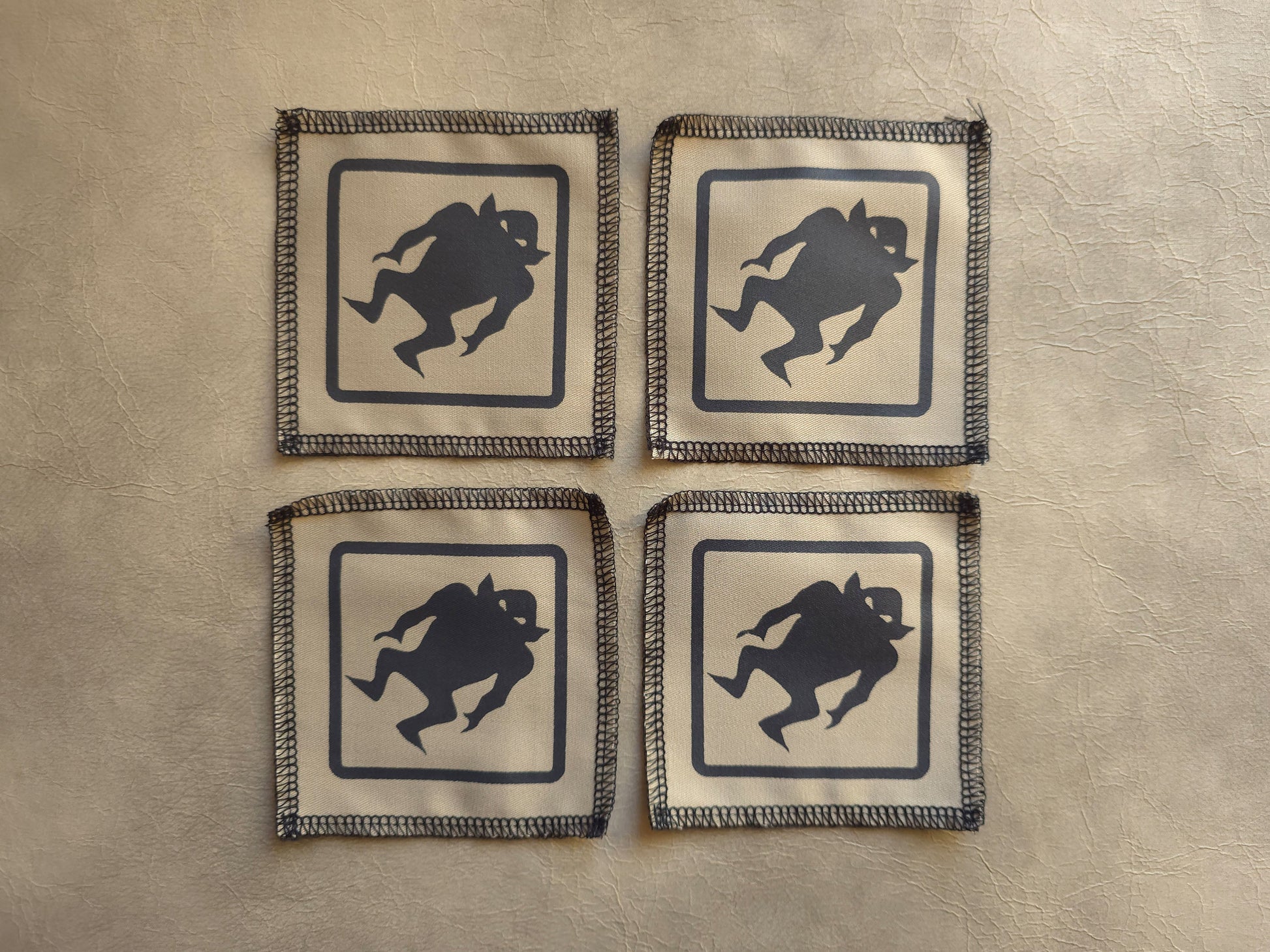 Beige handmade screen printed monster warning symbol patches arranged in a group display