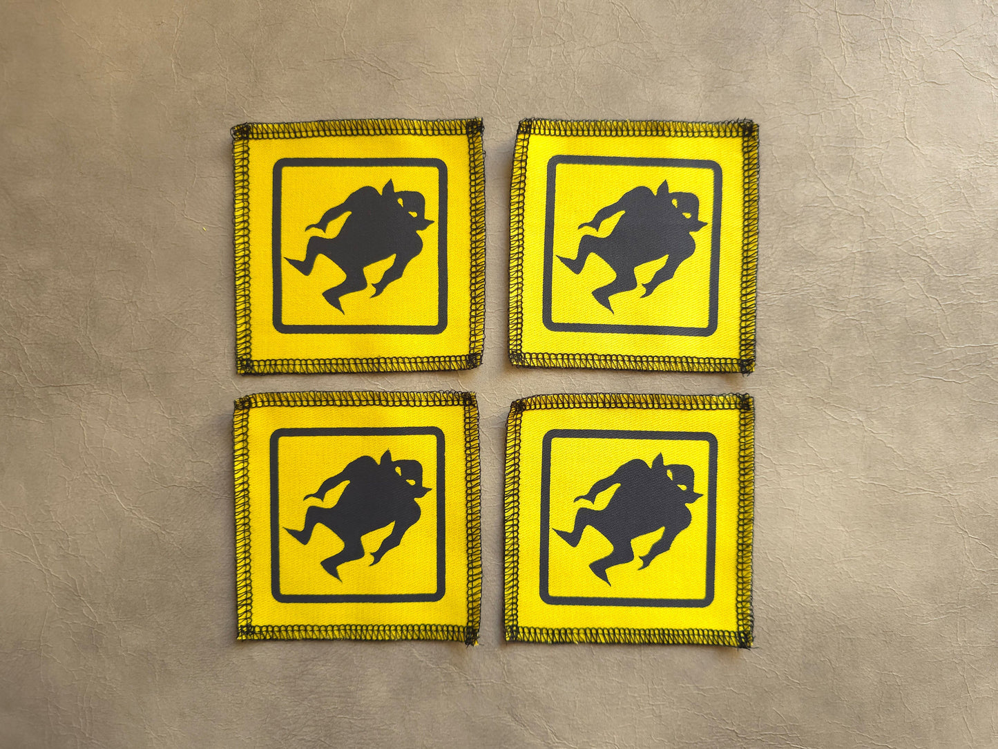 Set of yellow handmade screen printed monster warning symbol patches displayed together