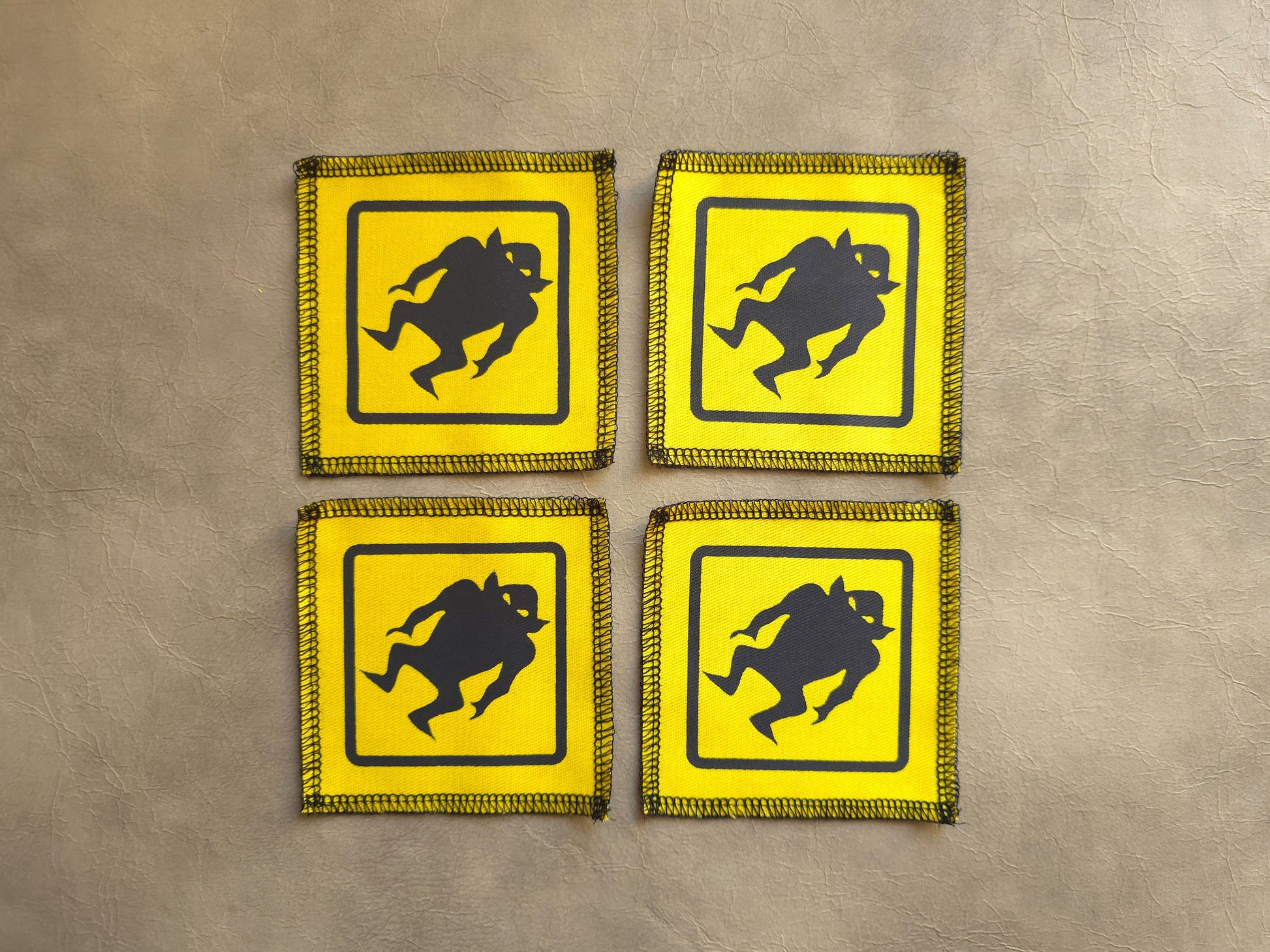 Set of yellow handmade screen printed monster warning symbol patches displayed together