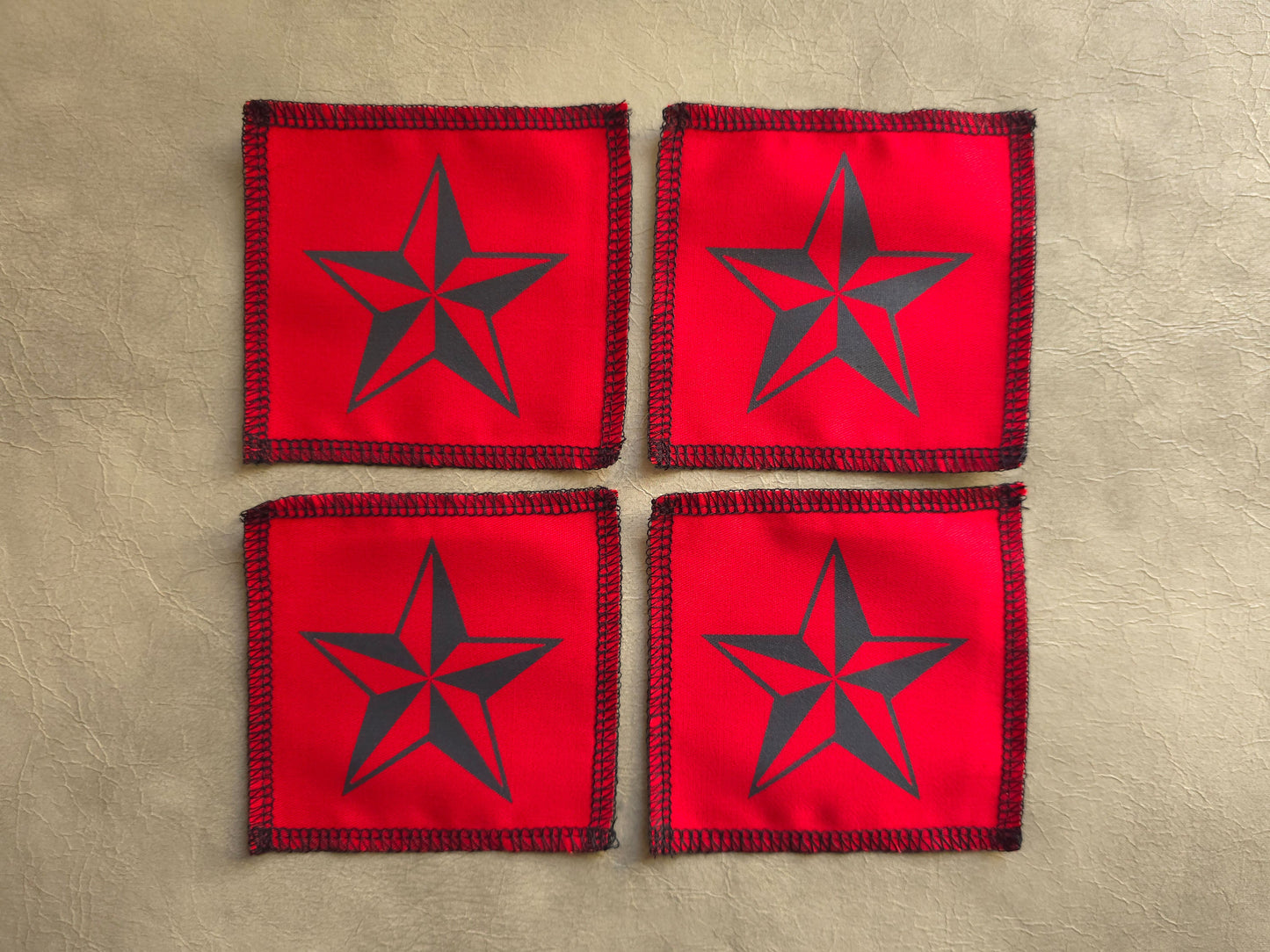 handmade screen printed Four red coasters with black star design on a beige surface
