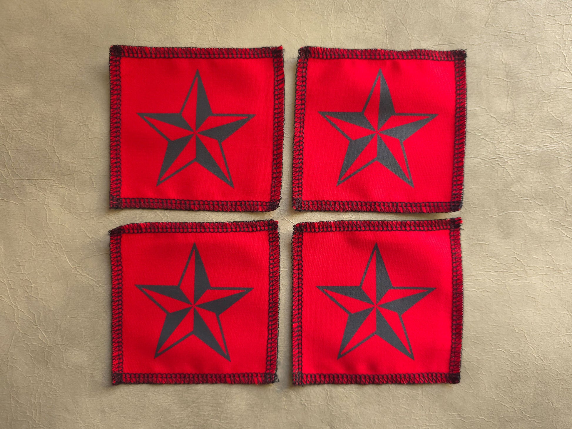 handmade screen printed Four red coasters with black star design on a beige surface