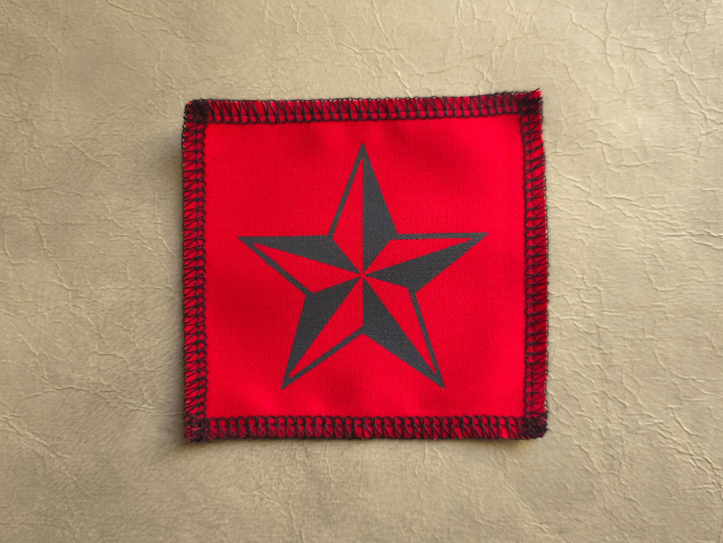 Red square patch with a black star on a beige background