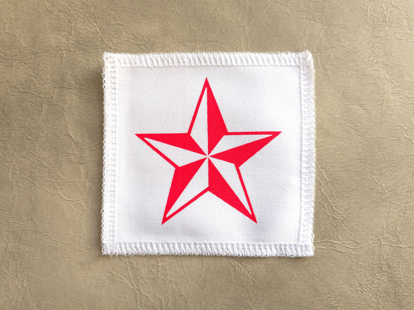 handmade screen printed White patch with a red star on a beige background