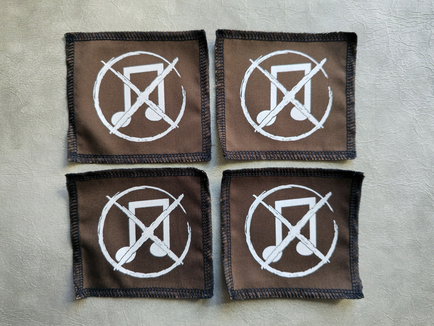 Brown handmade screen printed noise not music symbol patches displayed in a group layout