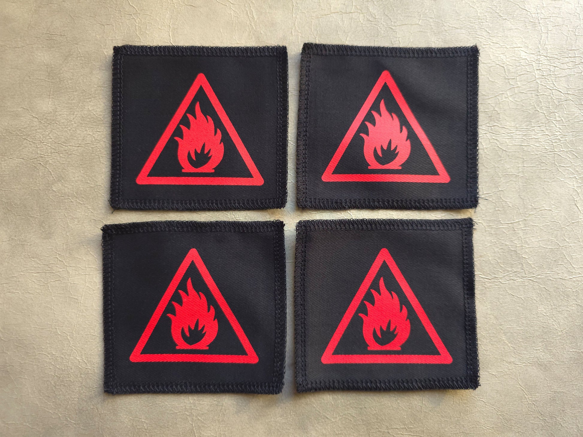 Four black patches with red fire triangle symbols on a beige surface