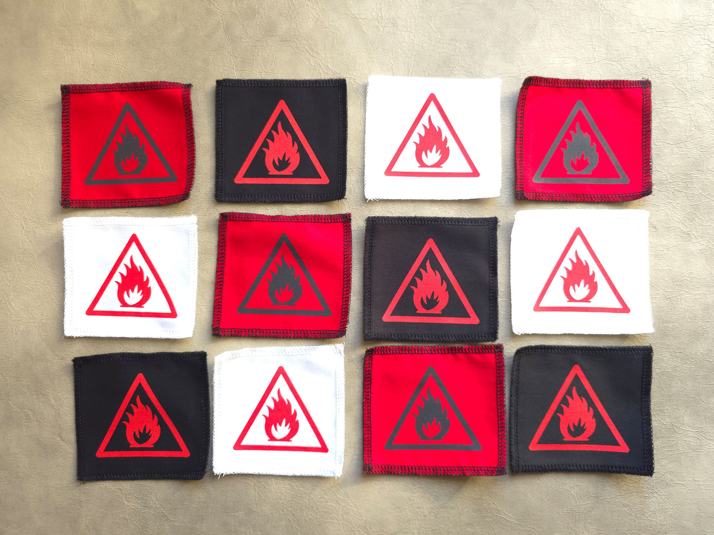 Handmade screen printed open flame symbol patch. Patches with fire hazard symbols arranged in a 3x3 grid on a beige background.